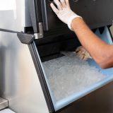 A man getting ice out of a commercial ice machine.