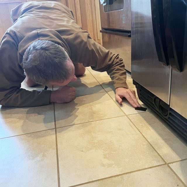 A man trying to keep something under fridge to balance it